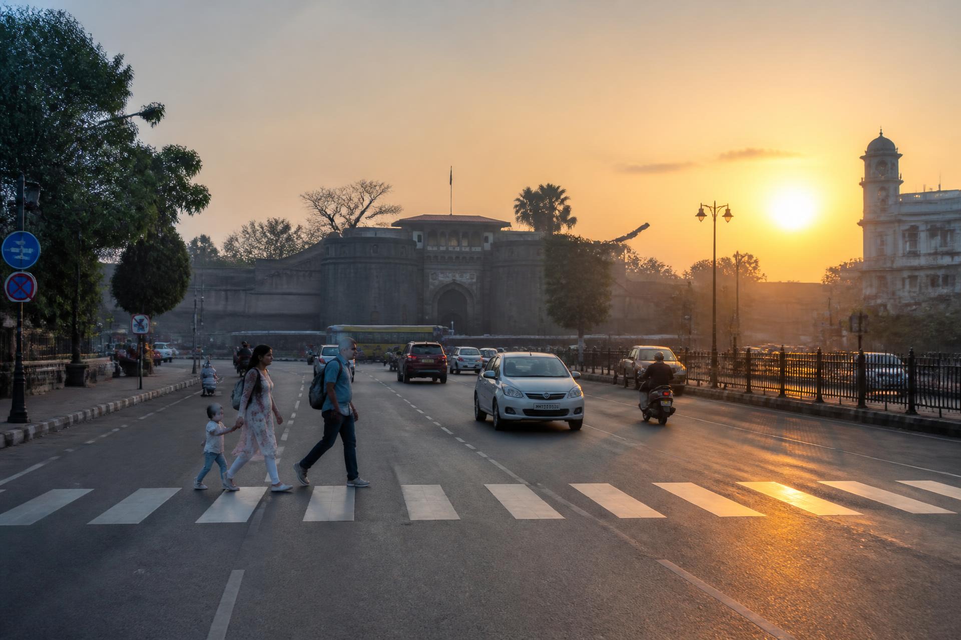 An Indian street at sunrise: a family crossing safely at a zebra crossing